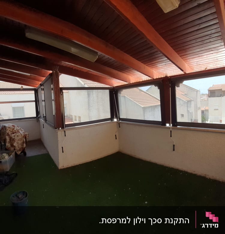 מרפסת מקורה עם חלונות זכוכית ומסגרות עץ.